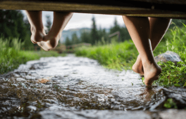 duas pessoas com os pés quase tocando um rio pequeno